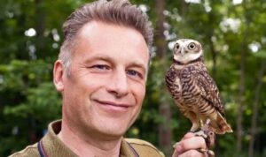 Chris Packham with an owl sitting on his hand