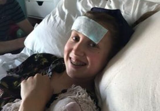 A picture of Patience smiling on her hospital bed at Alder Hey