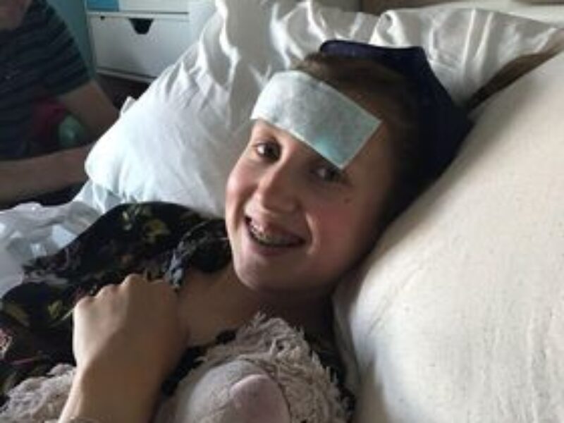 A picture of Patience smiling on her hospital bed at Alder Hey