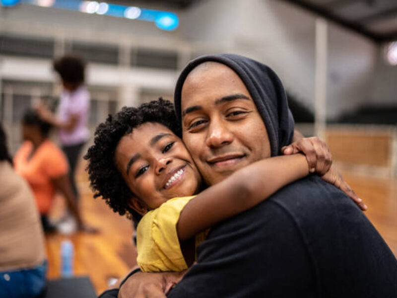 Portrait of father and daughter embracing at a community center