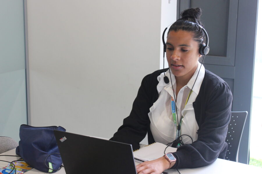 Woman on a headset looking at a laptop